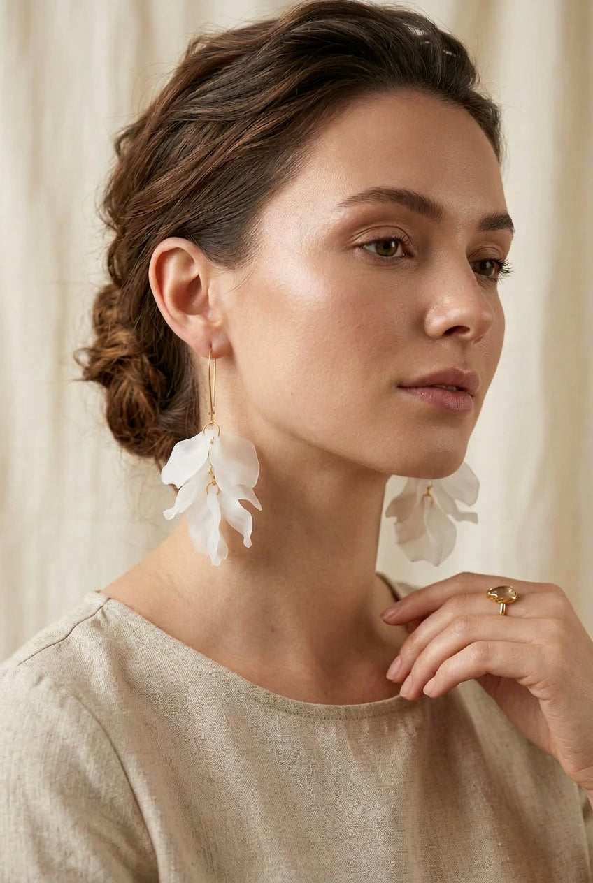 Pair of earrings on a black stand against a light blue background